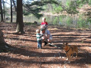 Modern dad multi-tasking, carrying one boy, checking a boo-boo, walking Lena. 